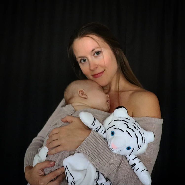 This is an image of a beautiful mother holding her newborn with a lovey from love by emi